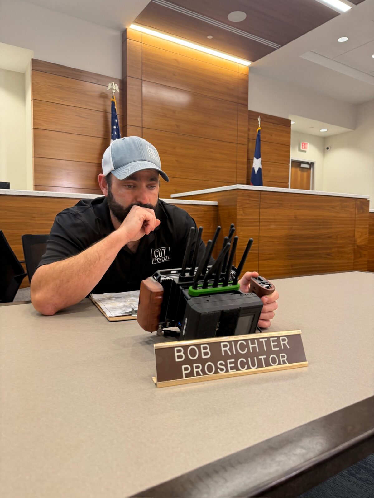 Crew member monitoring camera gear inside courtroom