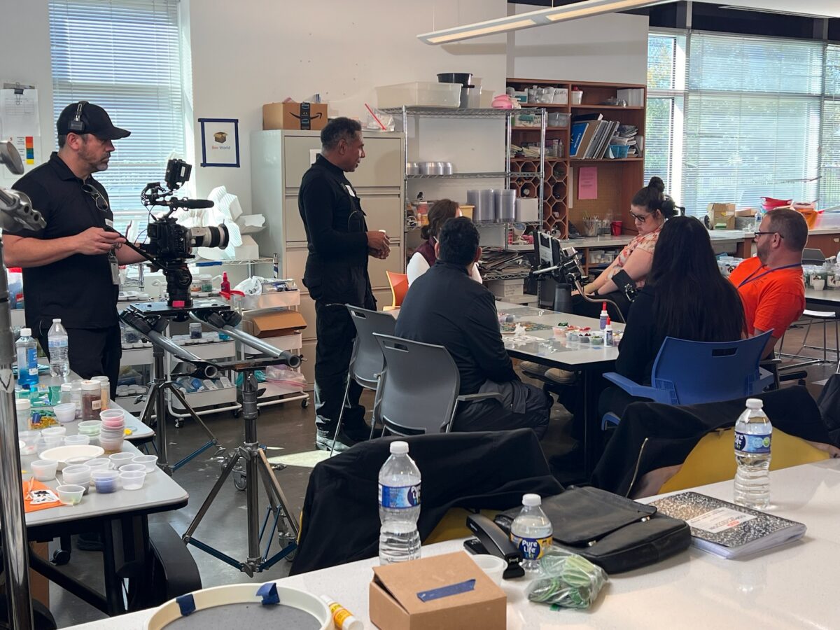 Behind the scenes of Cut To Create's project for Rice University's Kinder Institute for Urban Research, where a man films a group of people sitting around a crafting table.