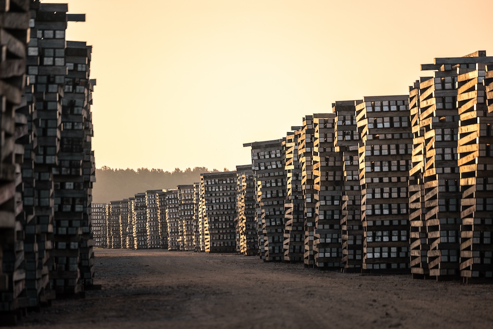 The sun sets above tall walls of stacked timber.