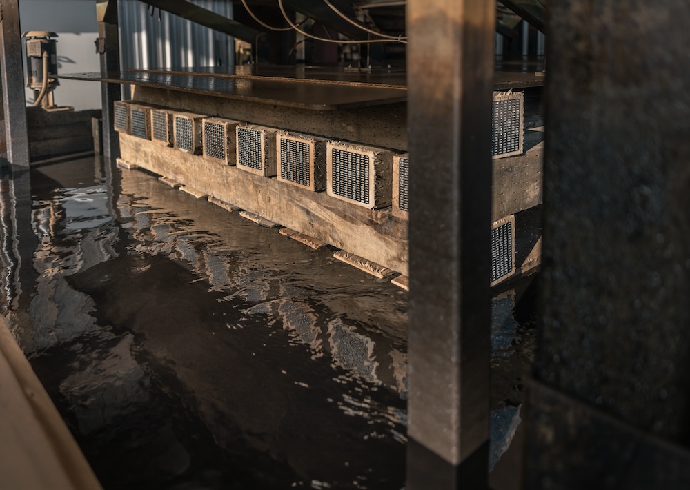 A short stack of timber sits in a shallow pool of water.
