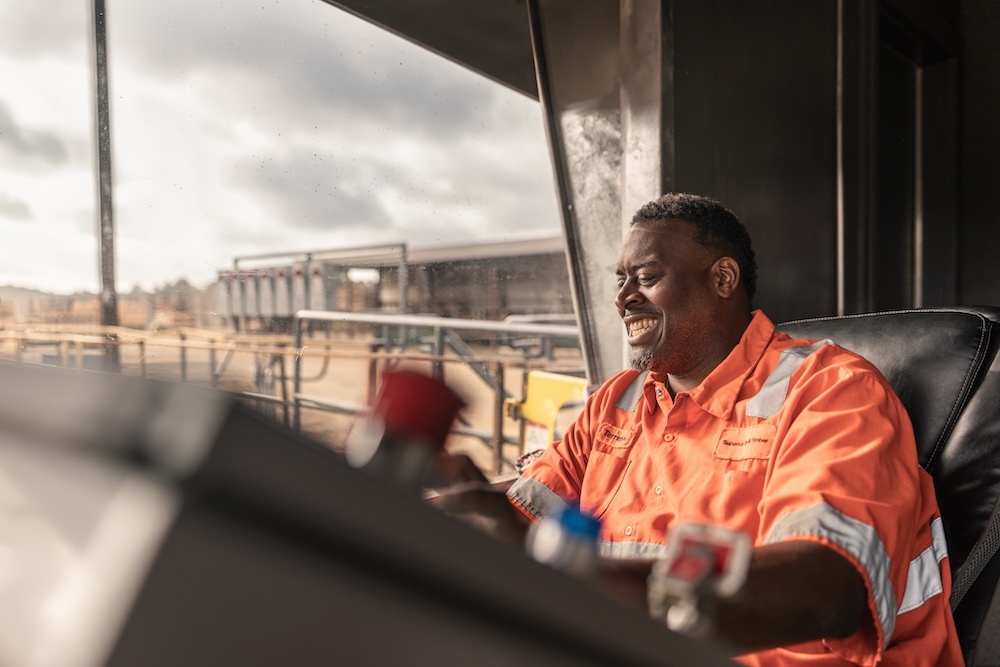 A worker laughs as he looks out a window at a timber facility.