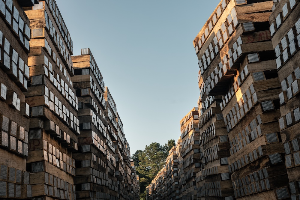 A clear blue sky shows between two large walls of stacked timber.